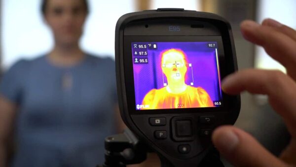 A woman is capturing an infrared image of her face using an FLIR E76 camera.